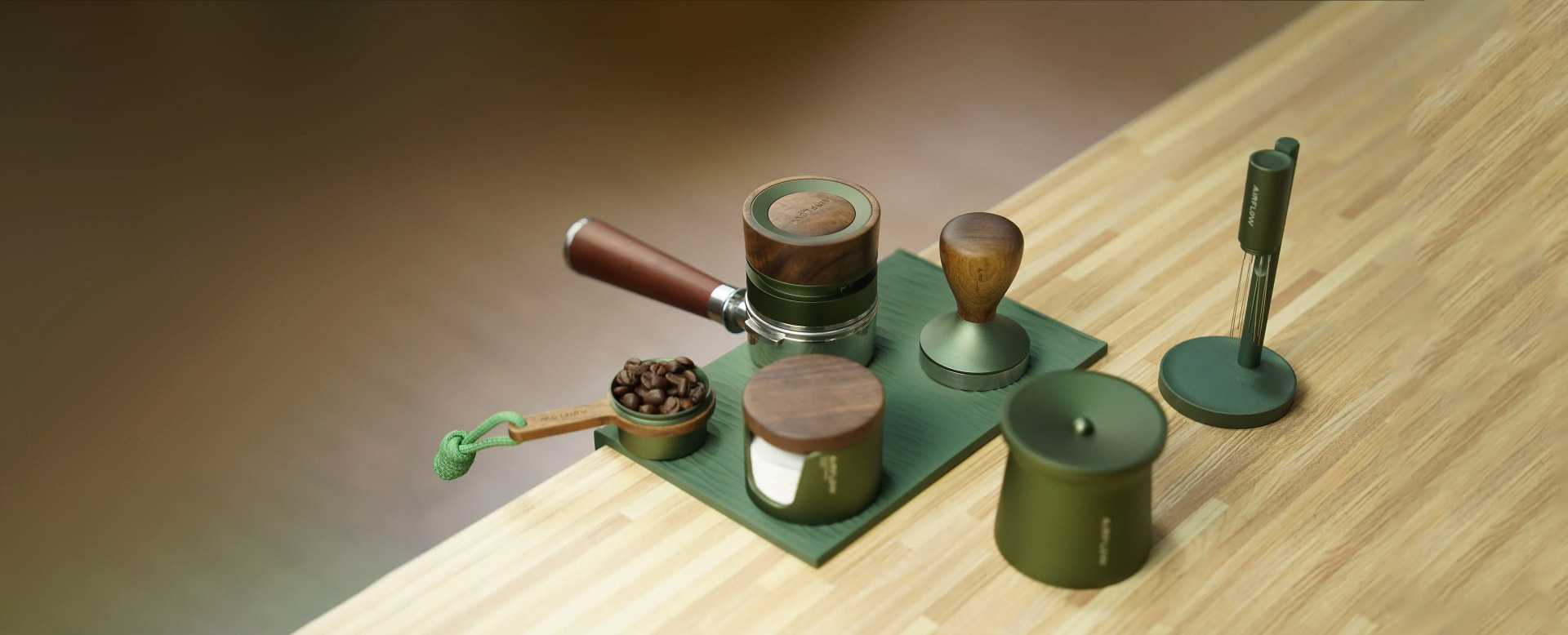 Airflow coffee tool range on display — tampers, dosing tools, scoops, jugs and cups in deep green, walnut and brushed steel on a wooden surface.