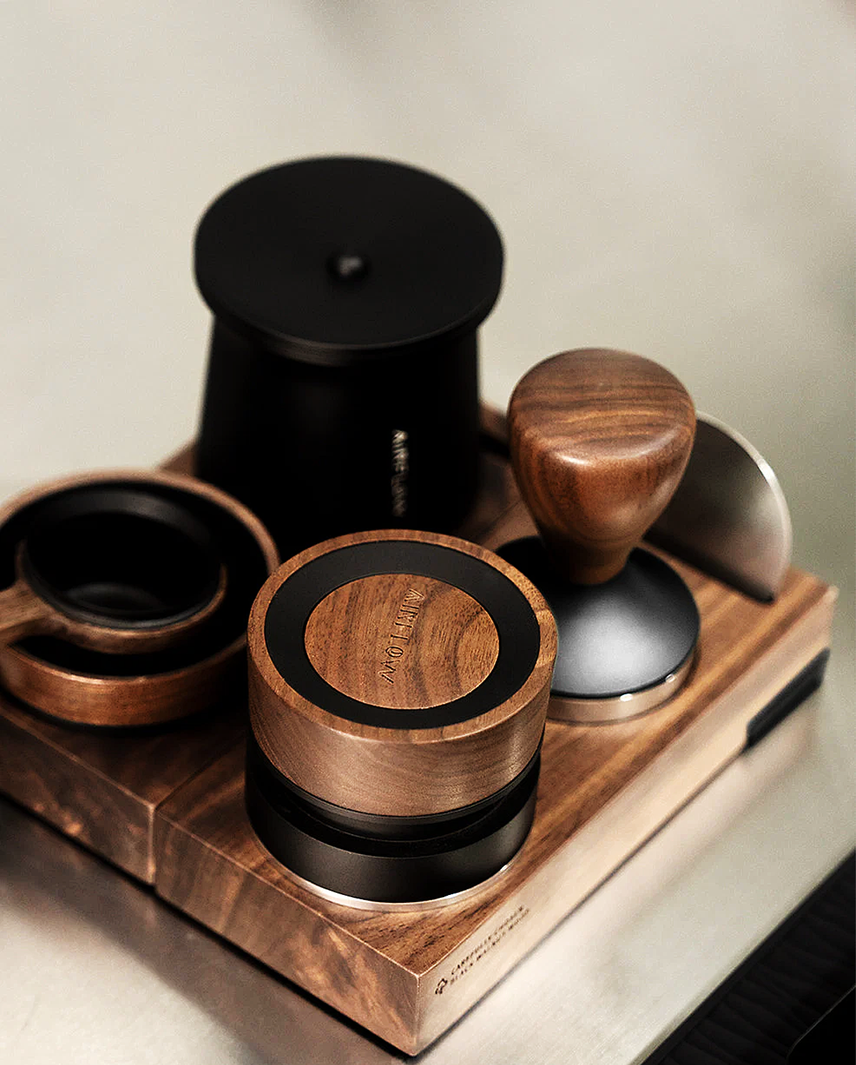 Airflow espresso tools arranged on a walnut gear holder, featuring a tamper, distributor and dosing cup.